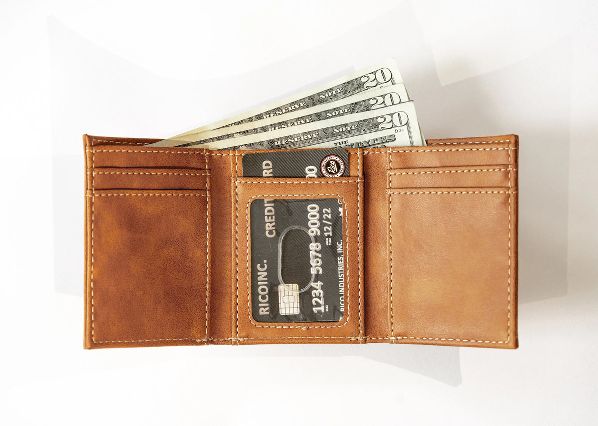 A brown North Carolina Tar Heels logoed leather bi-fold wallet shown open on a white background, with card slots, cash, and a credit card visible.